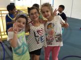 Three young girls pose for a picture in front of other children.