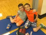 Two boys sitting on the floor with a lunch bag