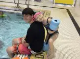 A man sitting in the pool with his arm around another person.