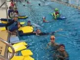 A group of people in the pool with floats.