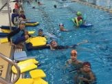 A group of people in the pool with floats.