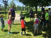 A group of children standing around in the grass.