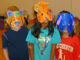 Three children with paper masks on their heads.