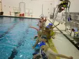 A group of people in the pool with water toys.