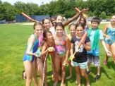 A group of children holding baseball bats in the grass.