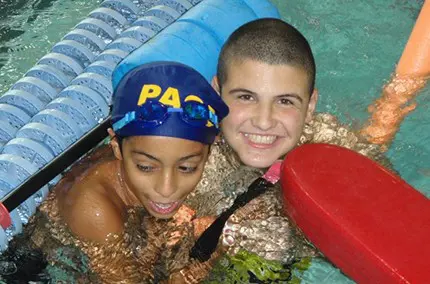 Two boys in the pool wearing swim caps