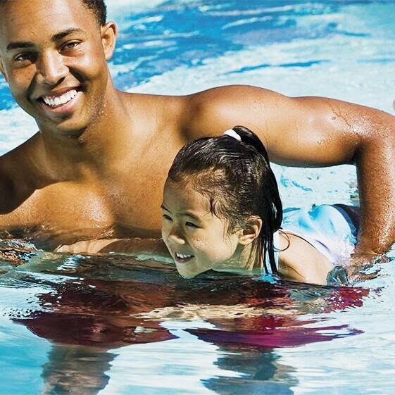 A man and young girl swimming in the pool.