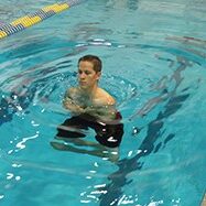 A man swimming in the pool with his arms out.